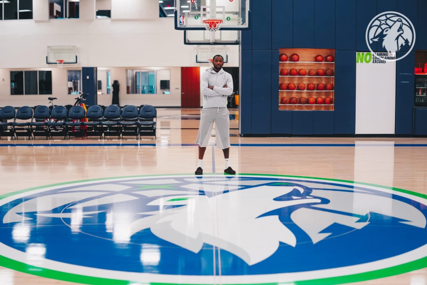 Jonathan Kuminga standing arms crossed on the Wolves logo at the practice facility