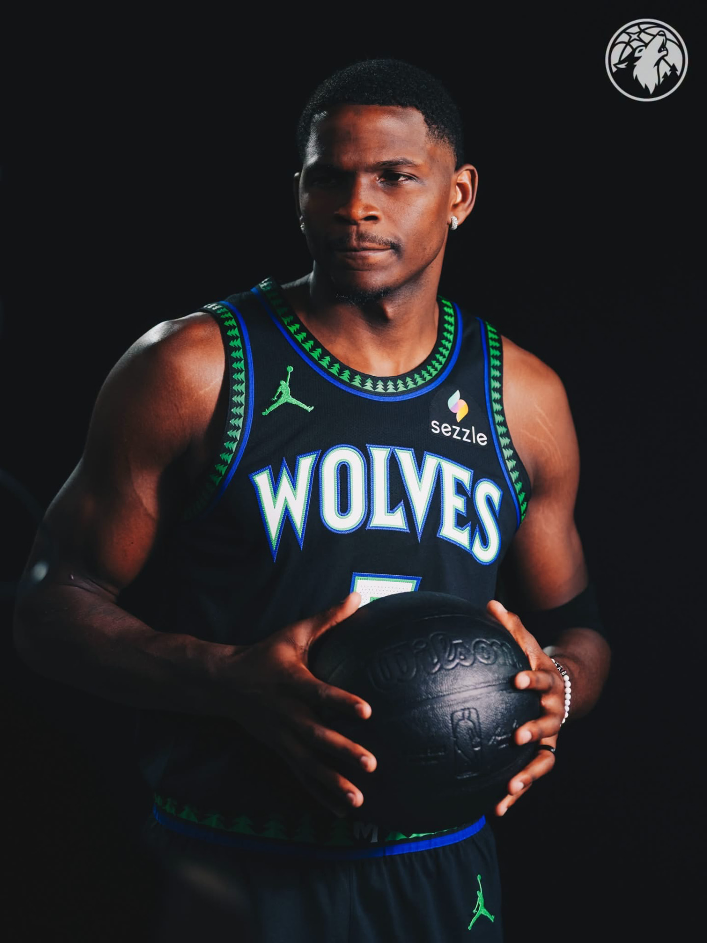 Anthony Edwards holding a black basketball in the black Wolves city edition jersey
