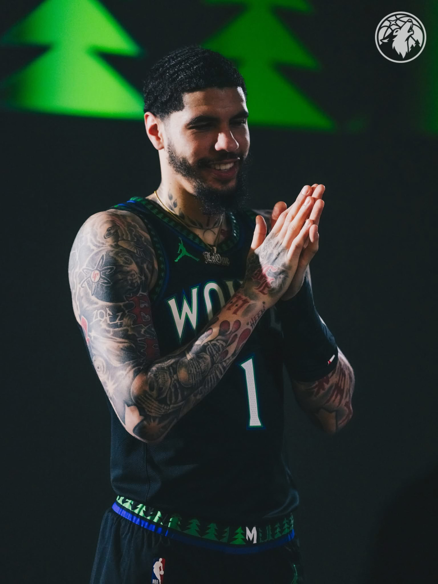 LaMelo Ball smiling and clapping in the black Wolves #1 city edition jersey under green tree lights